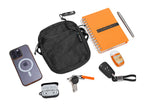Collection of everyday carry items including a black pouch, phone case, notebook, keys, and car keychain on a white background.