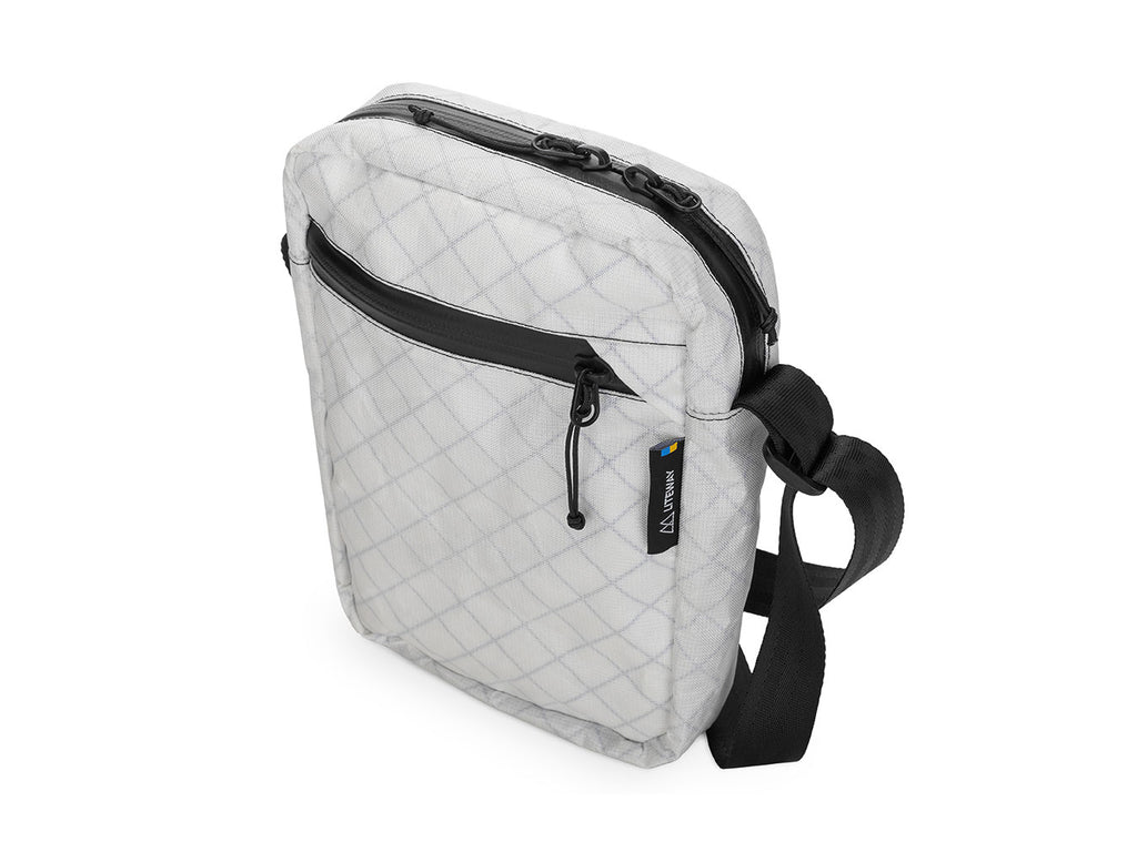 White quilted crossbody bag with black strap on a white background