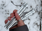 Hand holding a bundle of silver tent stakes against a blurred natural background